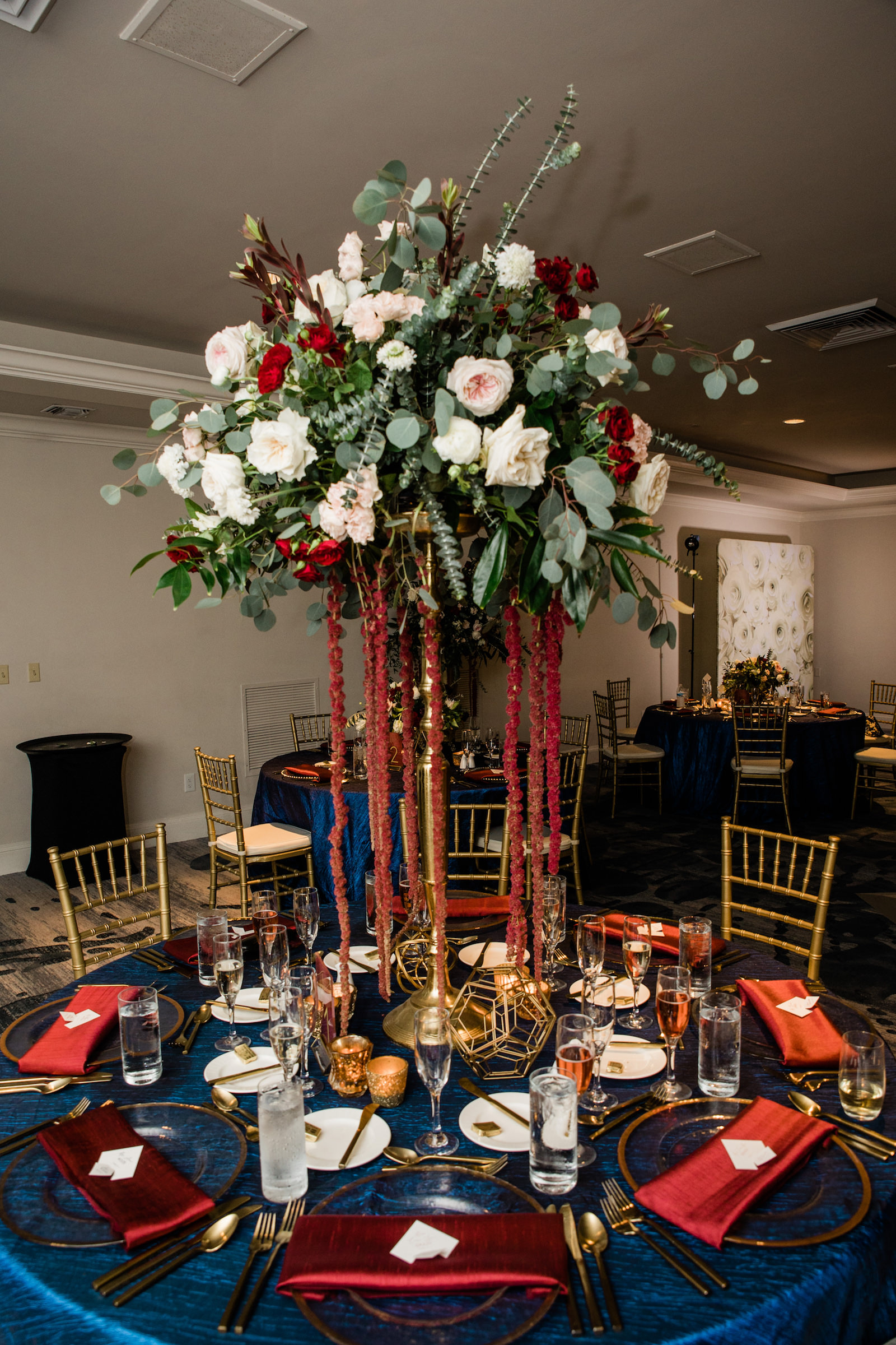 Elegant Navy Wedding Reception Decor, Tall Gold Vase with Greenery, Blush Pink and White Roses, Dark Purple and Red Flowers with Hanging Amaranthus Flower Centerpiece, Navy Blue Table Linen, Gold Chiavari Chairs | Tampa Bay Wedding Florist Botanica | St. Petersburg Wedding Venue The Don Cesar