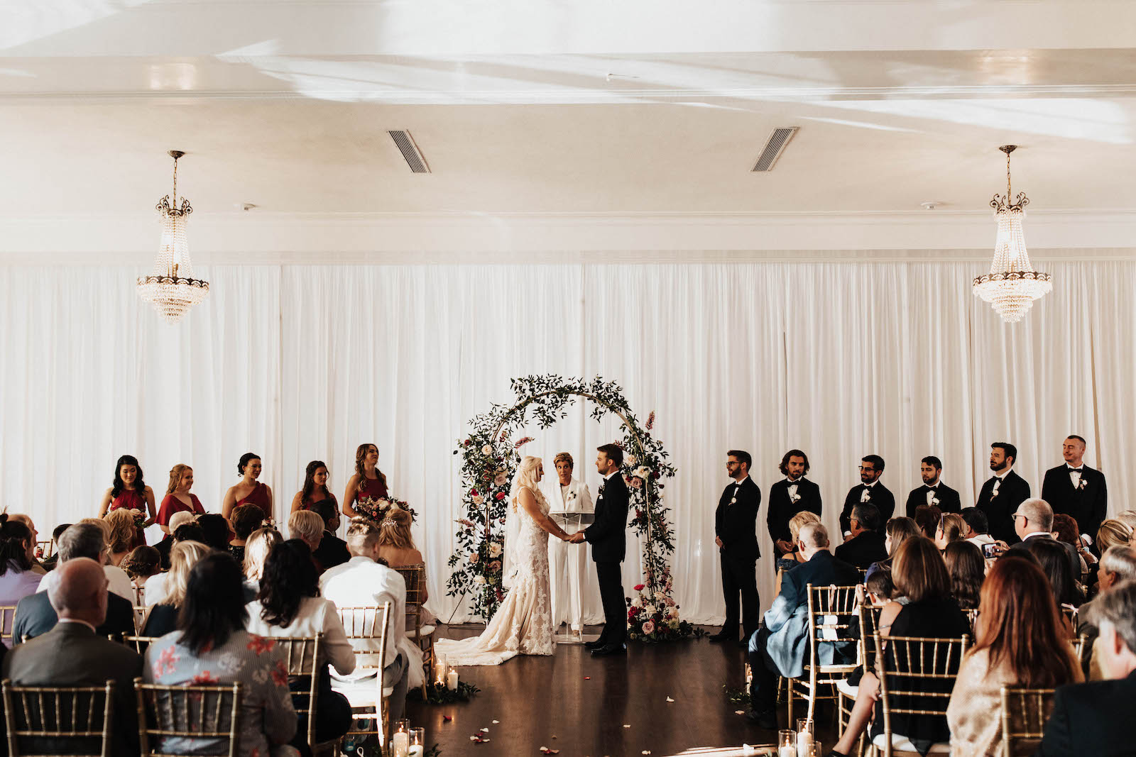 Warm Romantic Neutral Wedding Ceremony, Bride and Groom Exchanging Wedding Vows, Rounded Arch with Greenery, White Roses and Berry Color Flowers | Tampa Bay Wedding Planner Coastal Coordinating