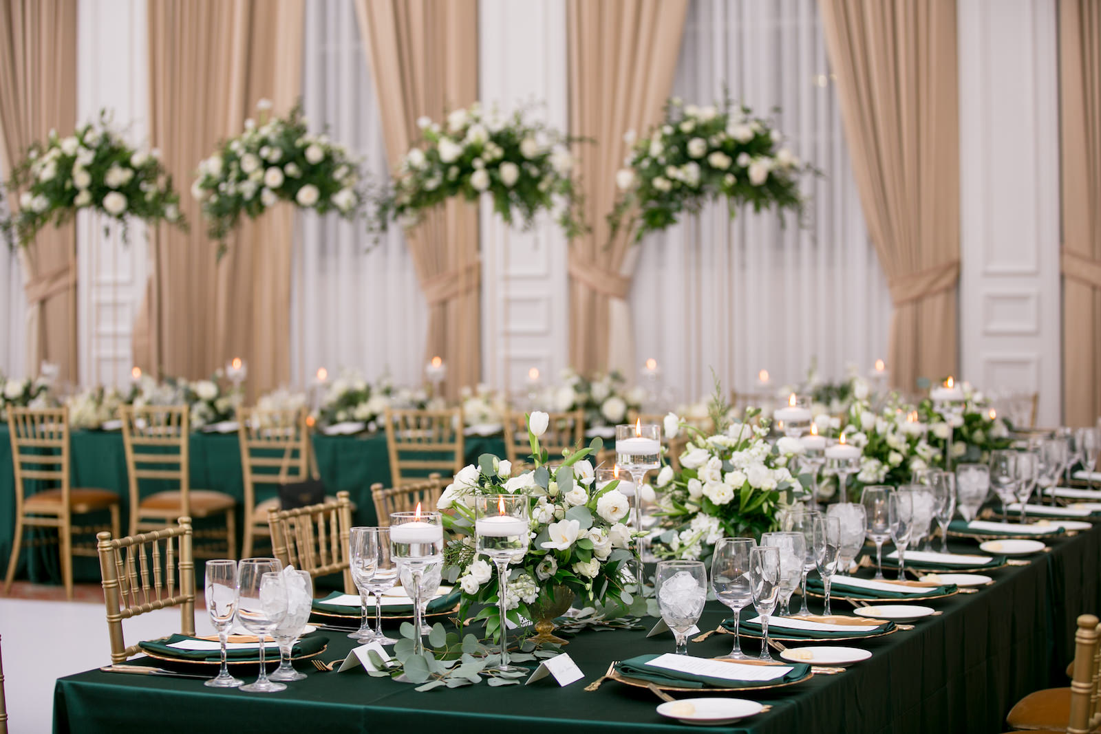Green and Gold Christmas Wedding Decor, Long and Round Tables with Emerald Green Table Linens, Gold Chiavari Chairs, Gold Chargers, White and Greenery Low and Tall Floral Centerpieces, Gold Monogram on Dance Floor | Tampa Bay Wedding Photographer Carrie Wildes Photography | Wedding Rentals Kate Ryan Event Rentals | Over the Top Rental Linens | A Chair Affair Event Rentals
