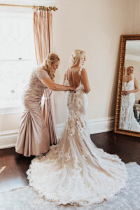 Warm Romantic Neutral Wedding, Mother Helping Bride Getting Lace and Illusion with Nude Lining Wedding Dress On
