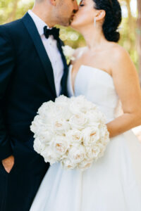 Modern Elegant Bride Holding Classic Round White Roses Floral Bouquet and Groom Outdoor Wedding Portrait