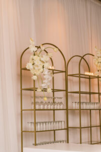 Timeless Classic Wedding Cocktail Hour Decor, Tall Gold Modern Rounded Shelves with Champagne, White Roses and Orchids Floral Arrangements | Tampa Bay Wedding Planner Parties A'la Carte | Wedding Florist Bruce Wayne Florals