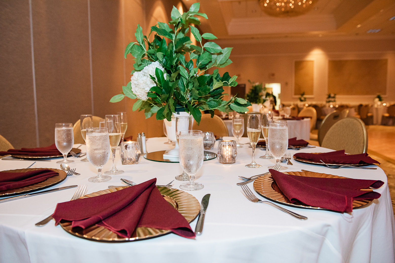 Burgundy Napkin with Gold Charger Wedding Tablescape and Greenery Centerpieces