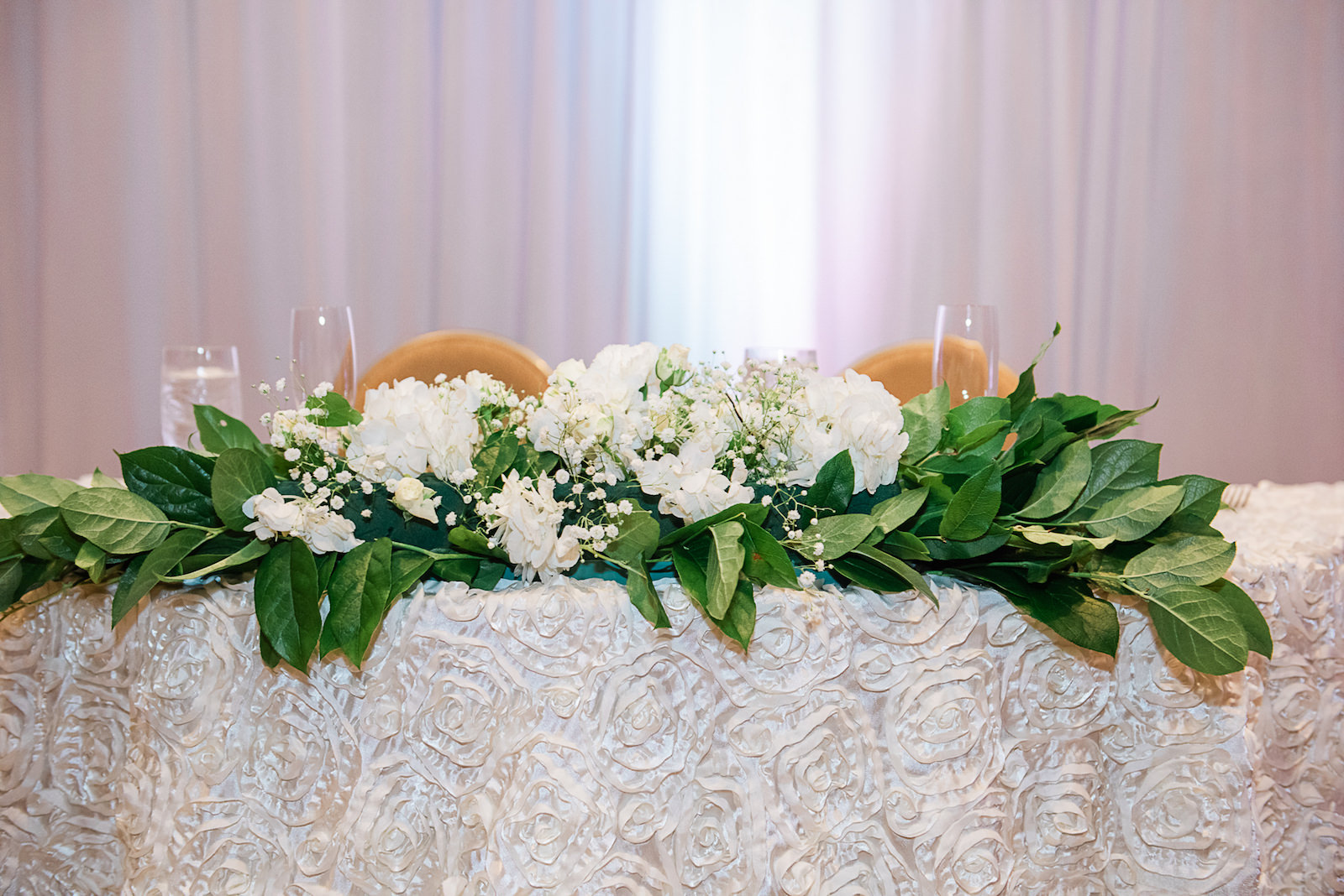 Sweetheart Table with White Embellished Linen and Greenery with White Florals