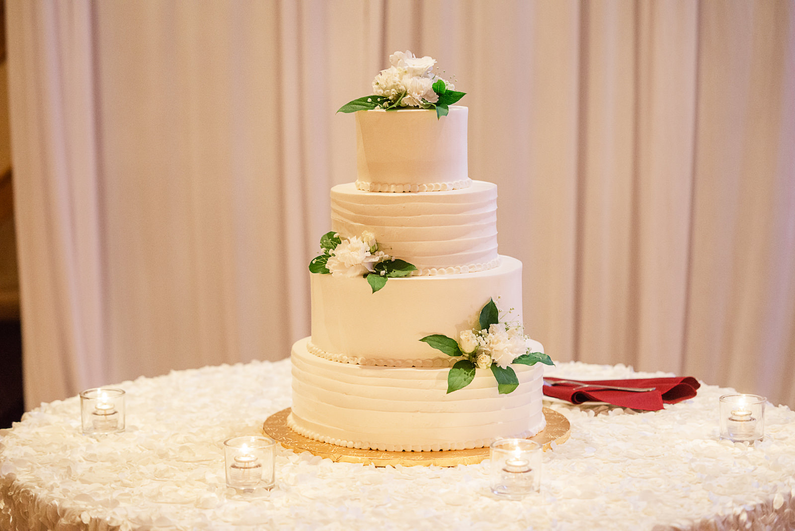 Four Tier White Wedding Cake with Greenery and White Floral Detail
