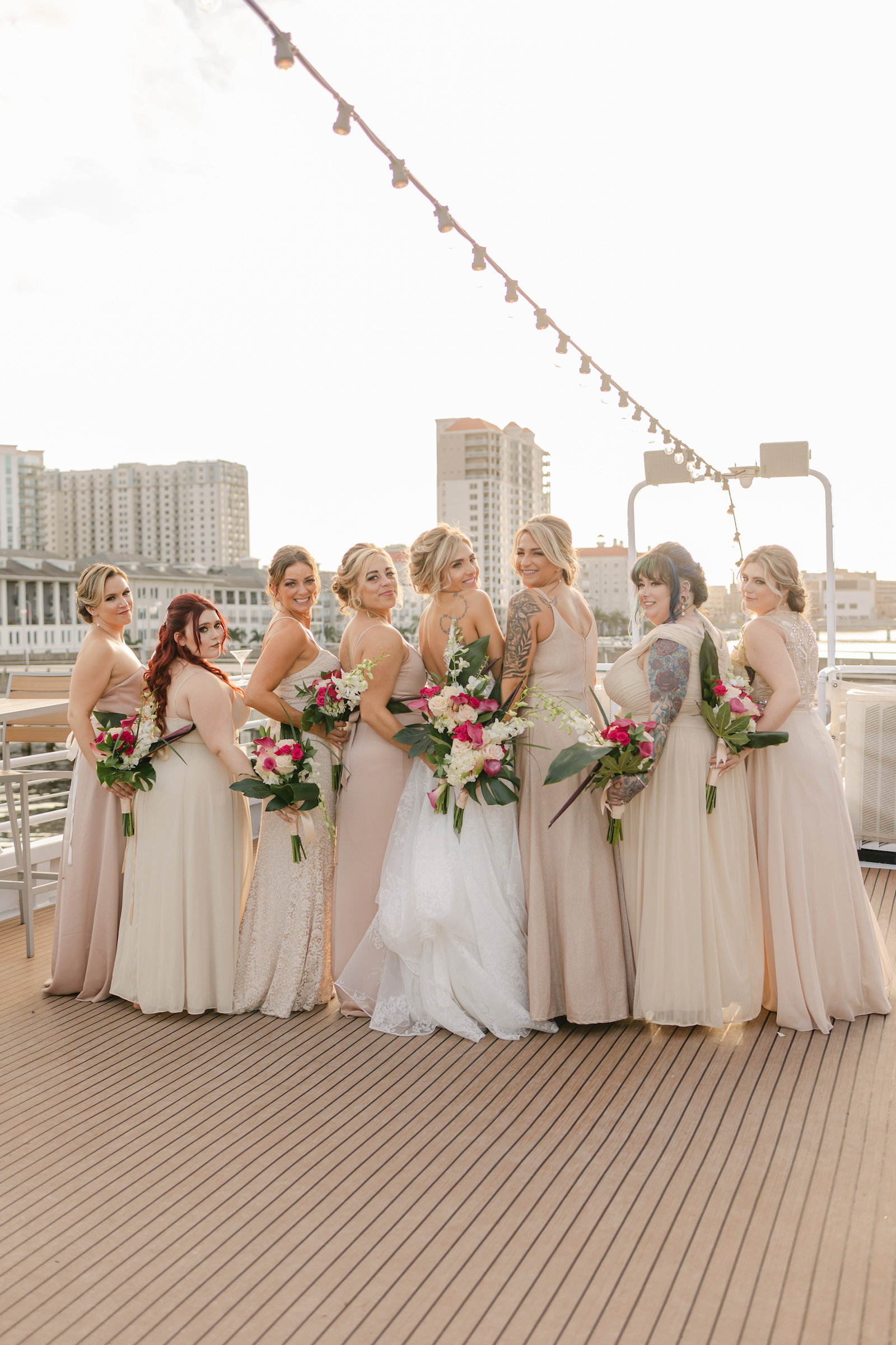 Bride and Bridesmaids in Mix and Match Tropical, pink, white, yellow, Sand Dresses Holding | The Yacht StarShip