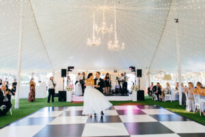 Modern Elegant Tent Wedding Reception with Hanging Chandeliers, String Lights, Live Band, Bride and Groom Dancing on Black and White Checkered Dance Floor