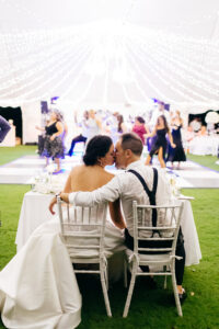 Romantic Modern Bride and Groom Kissing at Sweetheart Table in White Chiavari Chairs, Tent Wedding Reception