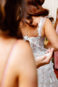 Fairytale Red and Pink Wedding Bride Getting Wedding Dress Tied | Tampa Bay Wedding Photographer Dewitt for Love Photography