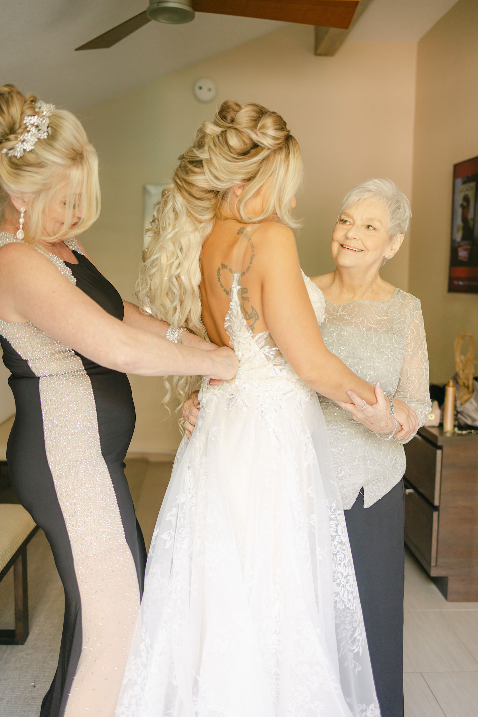 Bride Getting Wedding Ready Getting Dress Buttoned Up with Mom and Grandmother