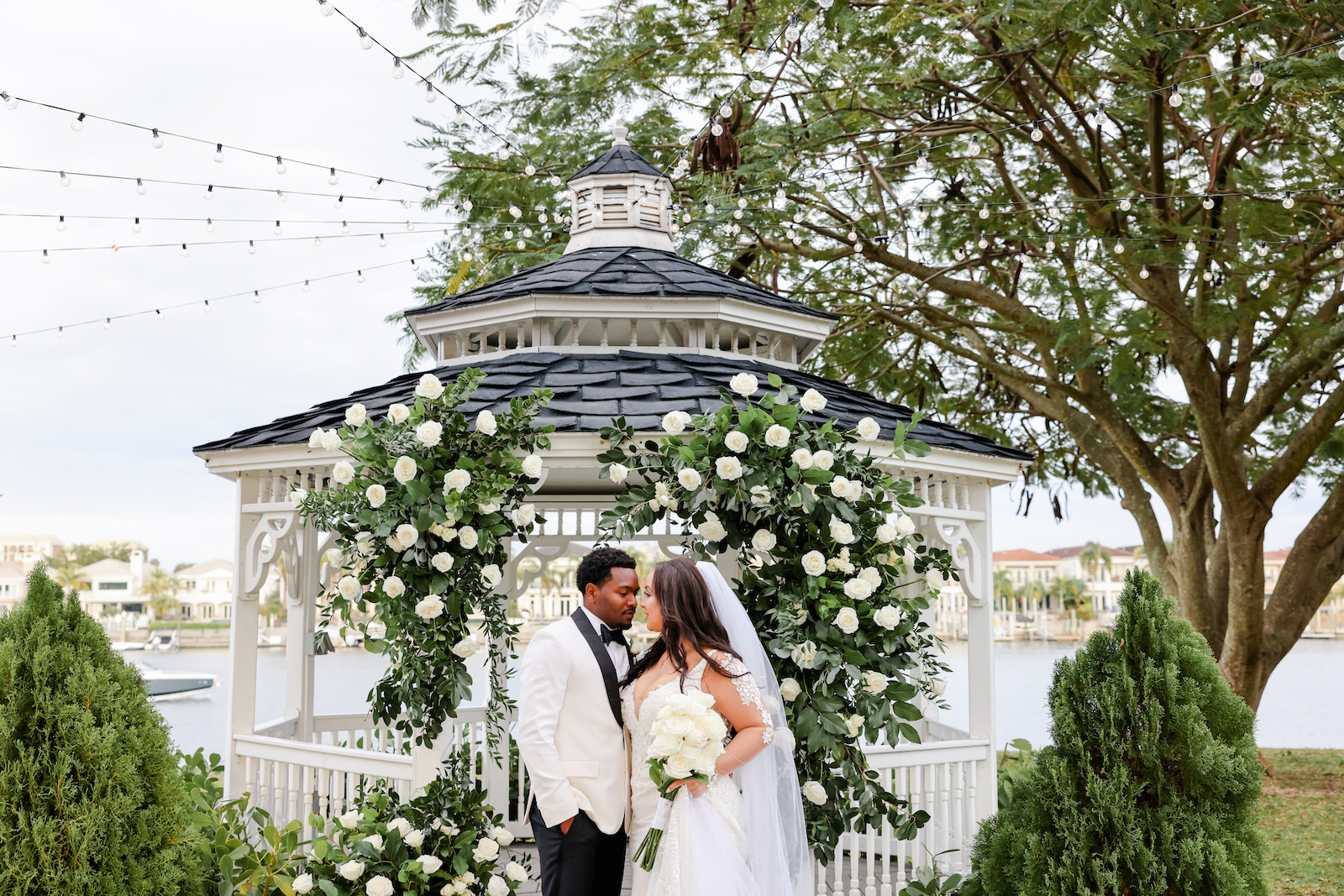 Modern Romantic Glam Bride and Groom Standing in Front of Waterfront Gazebo with Greenery and White Roses Arch | Tampa Bay Wedding Photographer Lifelong Photography Studio | Wedding Vennue Davis Islands Garden Club