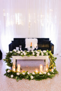 Modern Romantic Glam Wedding Reception Decor, Mirror Coffee Table with Greenery and White Roses Garland, Candlesticks, Black Couch | Tampa Bay Wedding Photographer Lifelong Photography Studio | Wedding Rentals Gabro Event Services