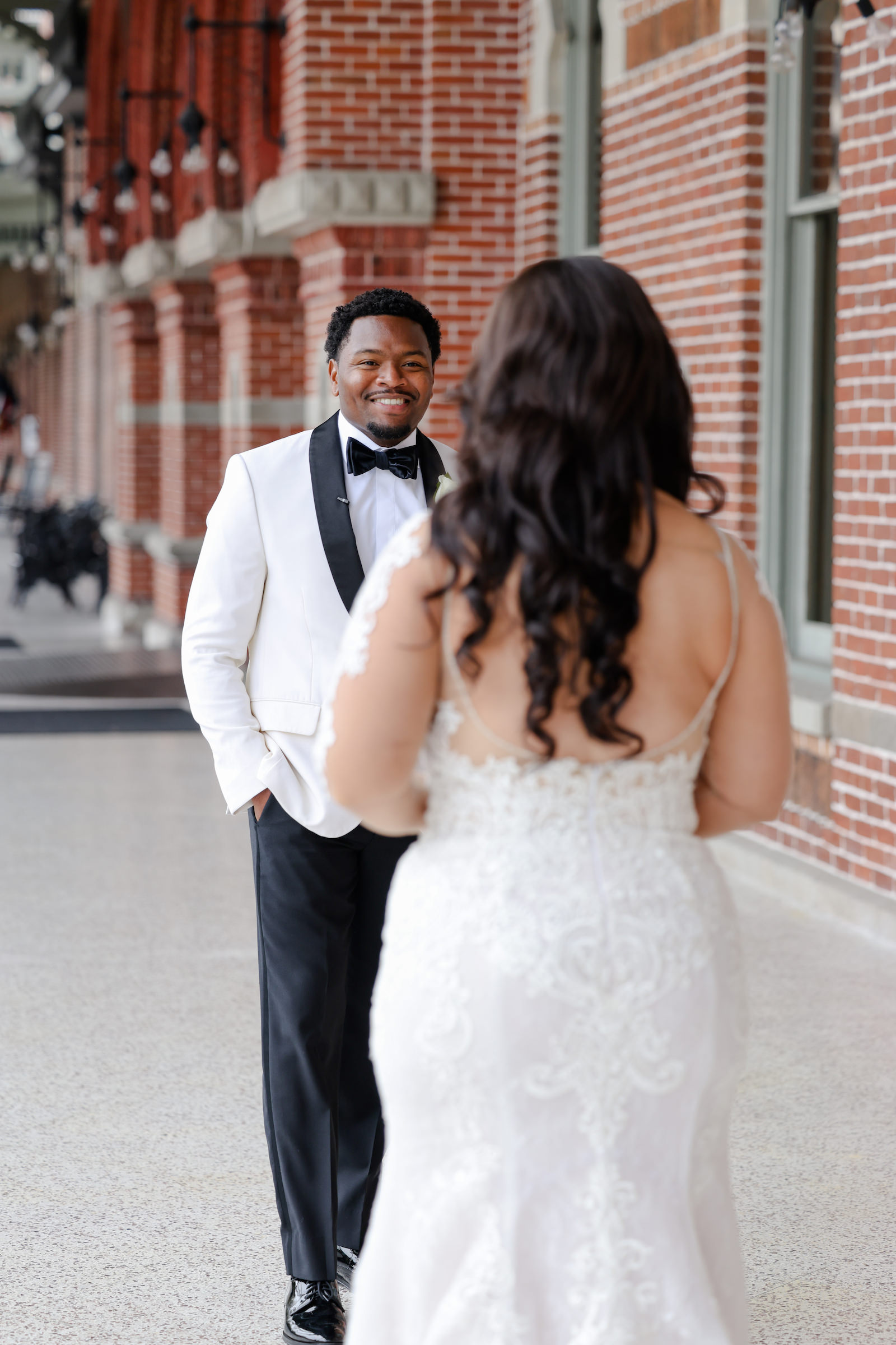 Modern Romantic Bride Wearing Lace and Illusion Long Sleeve Dress with Open Back Wedding Dress, Curled Hair Down First Look Wedding Portrait with Groom in White Tuxedo | Tampa Bay Wedding Photographer Lifelong Photography Studio | Wedding Hair and Makeup Femme Akoi Beauty Studio