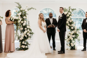 Winter Inspired Wedding, Bride and Groom Exchanging Wedding Vows During Wedding Ceremony, Greenery Pillars with White Roses Lush Floral Pillars | Tampa Bay Wedding Planner MDP Events | Safety Harbor Wedding Venue Harborside Chapel