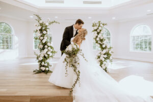 Winter Inspired Wedding, Bride and Groom Kissing After Wedding Ceremony, Greenery Pillars with White Roses Lush Floral Pillars | Tampa Bay Wedding Planner MDP Events | Safety Harbor Wedding Venue Harborside Chapel