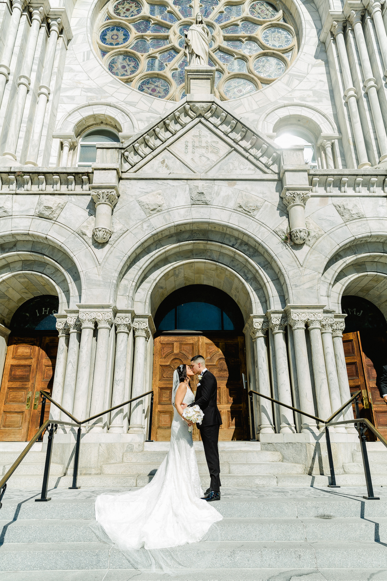 Romantic Bride and Groom Kissing on Staircase Outside Tampa Traditional Wedding Venue Sacred Heart Catholic Church