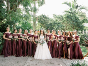 Romantic Royal Glam Gatsby Bride with Bridesmaids Wearing Burgundy Off the Shoulder Matching Satin Dresses Holding Pink Floral Bouquets | Tampa Bay Wedding Hair and Makeup Femme Akoi Beauty Studio