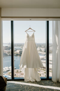 White Classic Wedding Ballgown Hanging in the Window Wedding Portrait