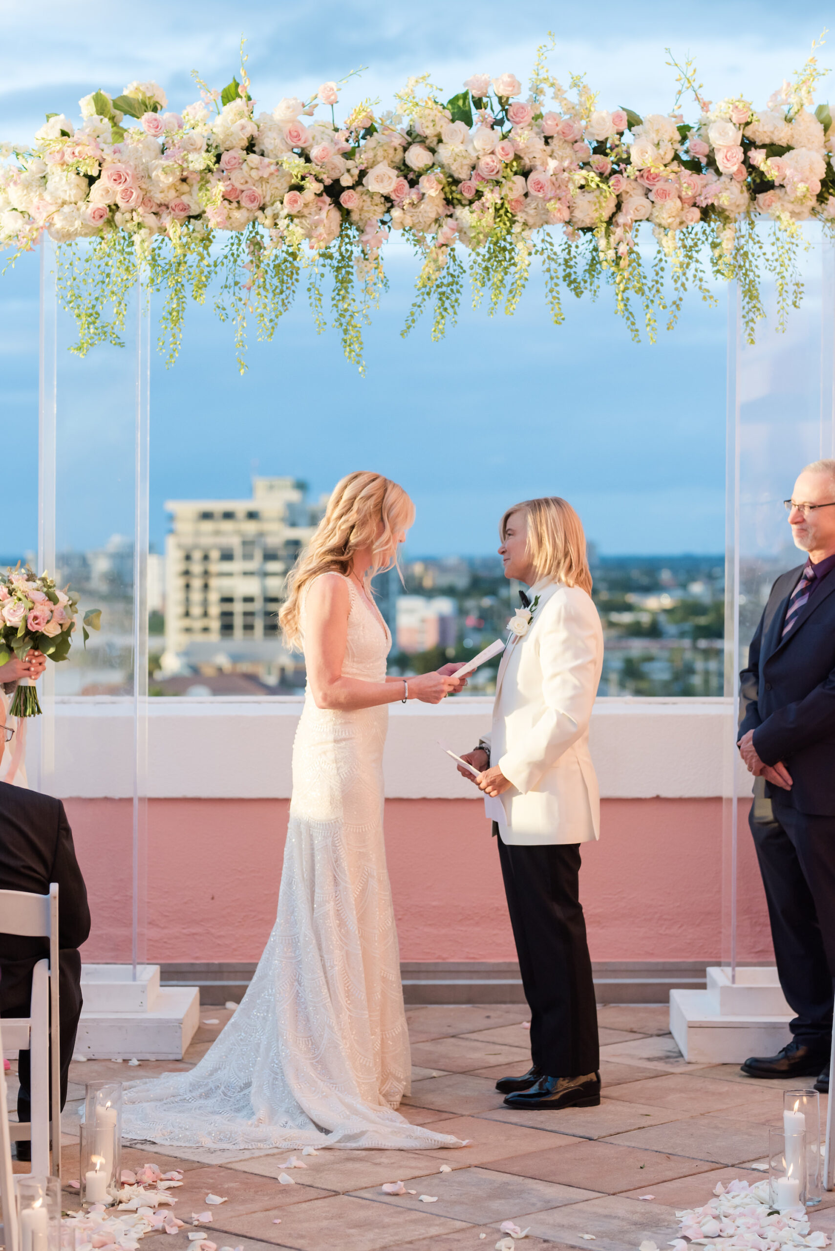 Lesbian Bride Exchanging Wedding Ceremony Vows, Elegant Blush Pink Same Sex Wedding, Modern Acrylic Arch with Lush Floral Arrangement, Hanging Greenery, White Hydrangeas, Blush Pink and Ivory Roses | Tampa Bay Wedding Photographer Amanda Zabrocki Photography | Clearwater Wedding Planner Elegant Affairs by Design | Wedding Florist Save the Date Florida | Rooftop Beach Waterfront St. Pete Wedding Venue The Don CeSar