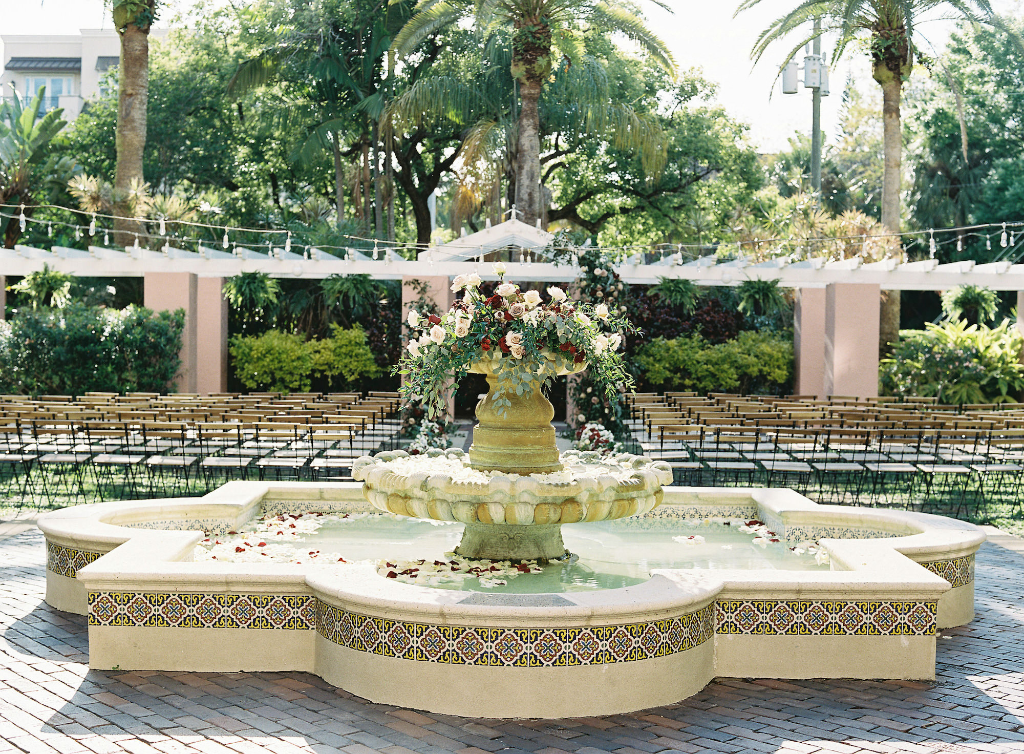Royal Glam Gatsby Elegant Outdoor Courtyard Wedding Ceremony Decor, Water Fountain with Greenery and White, Mauve and Red Roses Floral Arrangement | Tampa Bay Wedding Planner and Designer John Campbell Weddings | St. Pete Wedding Venue The Vinoy Renaissance