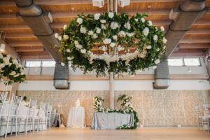 Winter Inspired Wedding Reception Decor, Lush Greenery and White Roses Floral Hanging Wreath, Sweetheart Table with Gray Table Linen Floral Garland | Tampa Bay Wedding Planner MDP Events | Wedding Venue Tampa River Center