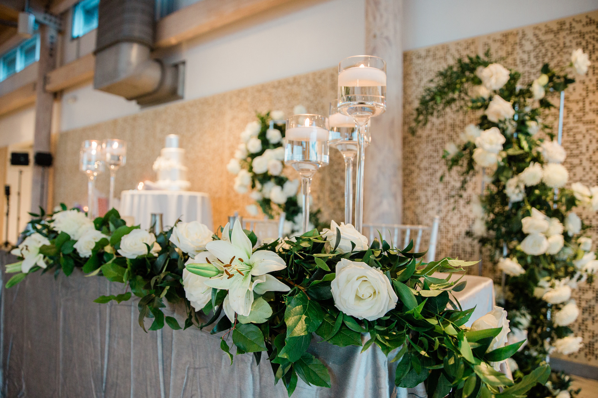 Winter Inspired Wedding Reception Decor, Sweetheart Table with Silver Table Linen, Greenery Garland with White Roses, Hydrangeas, Tulips Floral Garland, Floating Candles | Tampa Bay Wedding Planner MDP Events