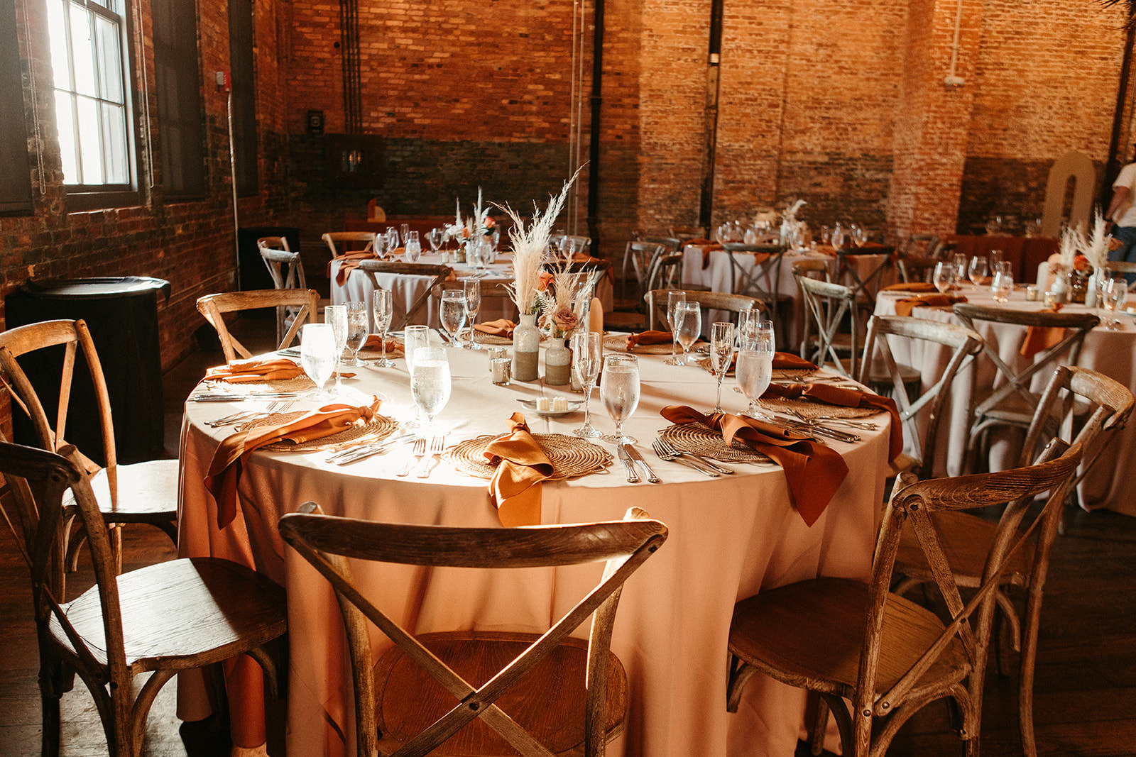 Earthy Neutral Boho Modern Chic Wedding Reception Decor, Round Tables with Terracotta Linens, Wooden Cross Back Chairs, Low Mix and Match Floral Pampas Grass Centerpiece | Tampa Bay Wedding Planner Wilder Mind Events | Wedding Venue Armature Works