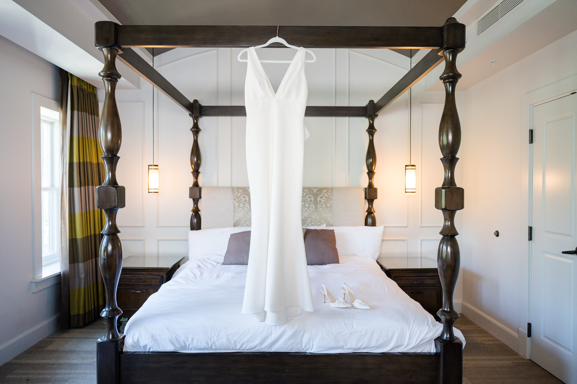 Sleek V-Neck Simple Wedding Dress Hanging From Bed Portrait