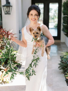 Old Florida Elegant Bride Wearing Classic Wedding Dress Holding Yorkie Dog and Greenery Leaf Leash