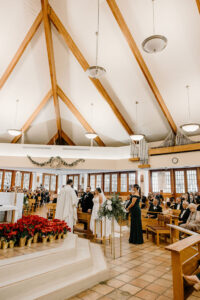 Bride and Groom at the Alter in Church Wedding Ceremony with Red Floral Accents | Tampa Wedding Florist FH Events