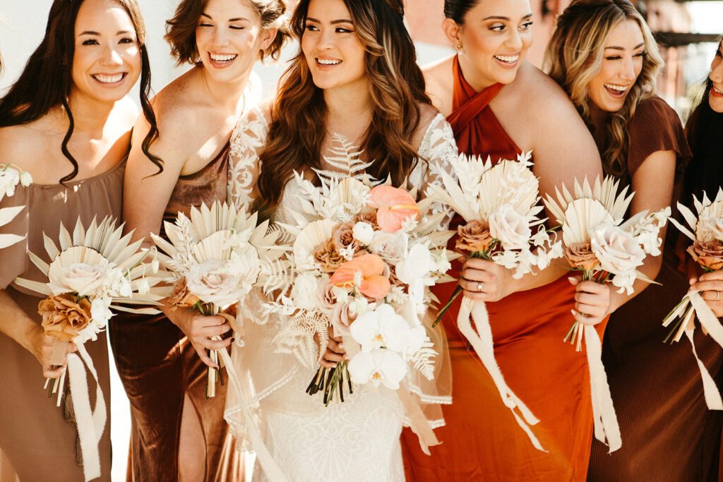 Earthy Neutral Boho Modern Chic Bridal Party, Bride Holding White Orchids, Pink Anthuriums, Dried Leaves Floral Bouquet, Bridesmaids Wearing Mix and Match Terracotta, Gold and Bronze Dresses | Tampa Bay Wedding Venue Armature Works | Wedding Florist Save the Date Florida | Femme Akoi Beauty Studio