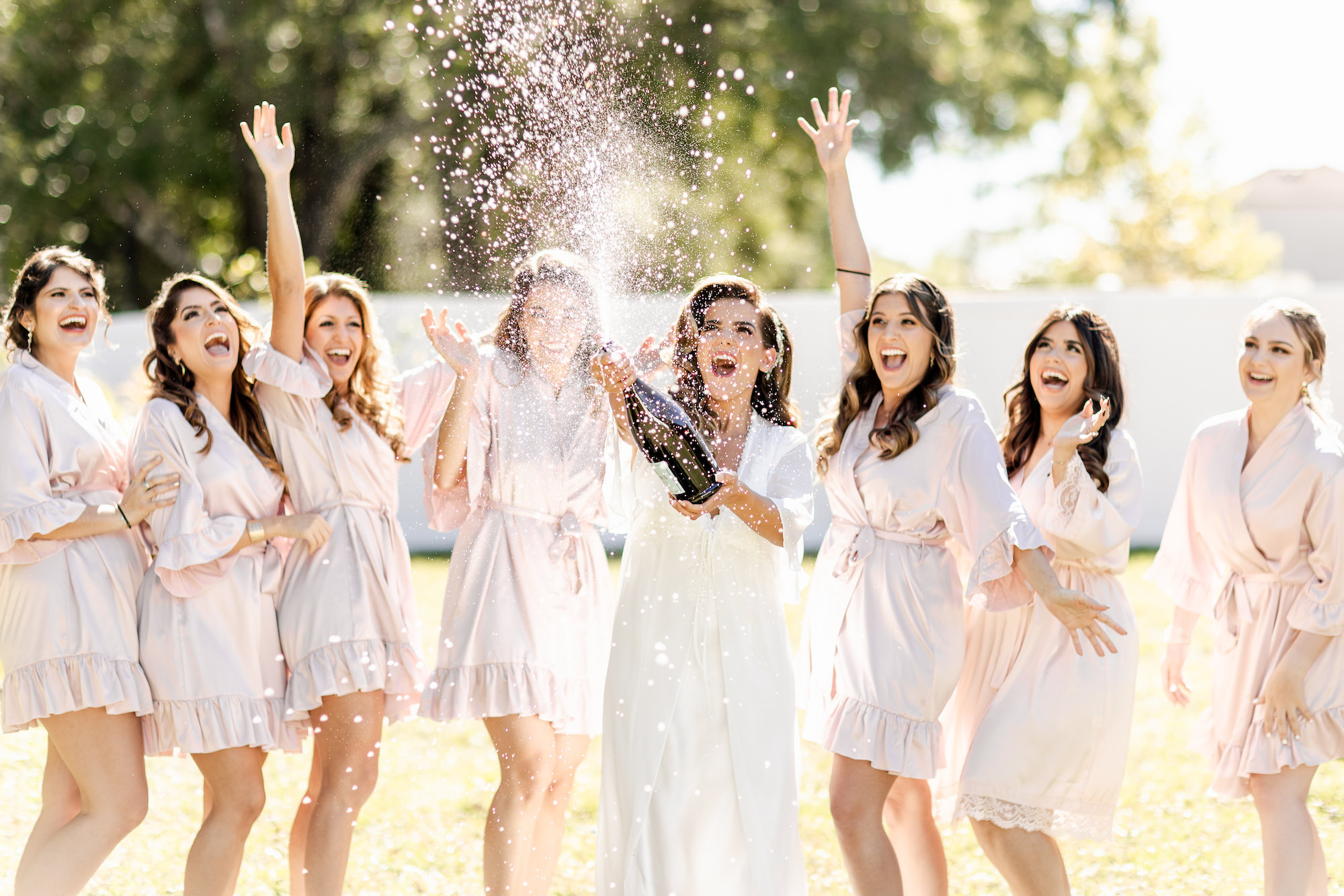 Fall Boho Bride and Bridesmaids with Popping Bottle of Champagne and Matching Pink Robes | Tampa Bay Wedding Hair and Makeup Femme Akoi Beauty Studio