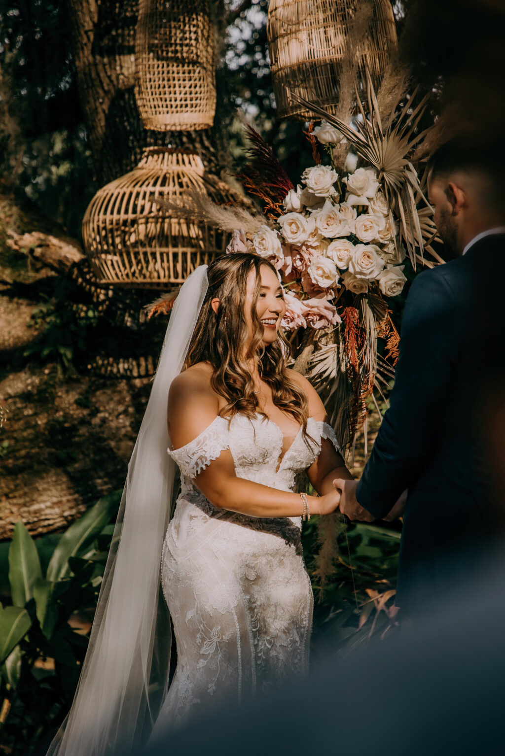 Bride and Groom Exchanging Wedding Vows, Boho Vintage Wedding Ceremony Decor, Lush Neutral Pampas Grass, Blush Pink and White Roses, Dried Palm Leaves, Terracotta Flower Arrangement on Geometric Hexagon Wooden Arch, Hanging Wicker, Rattan Lamp Shades on Trees | Tampa Bay Wedding Planner Stephany Perry Events | Wedding Venue Mill Pond Estate