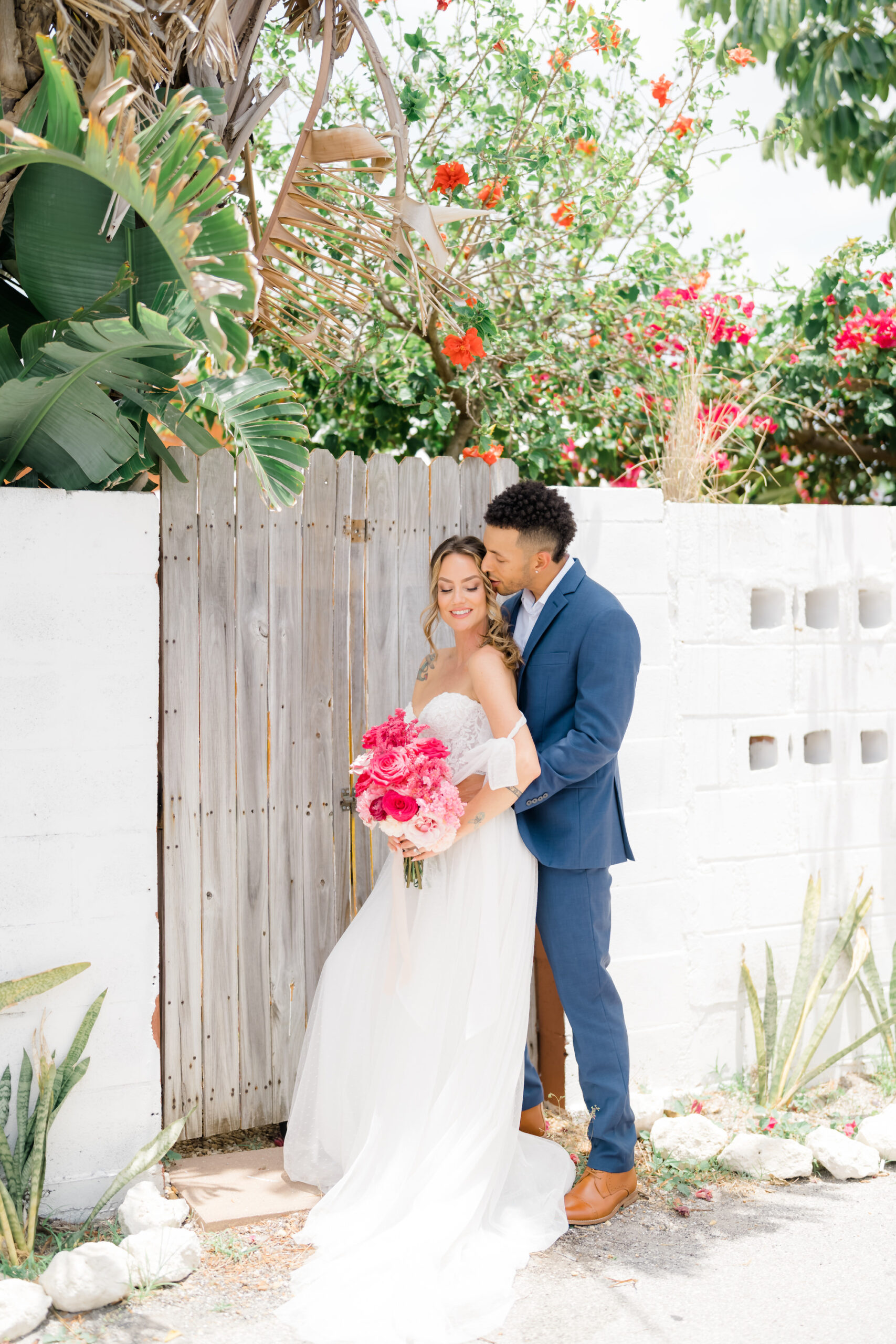 Bride Holding Pink and Fuchsia Floral Bouquet and Groom in Blue Suit Wedding Portrait | St. Pete Beach Wedding Venue The West Events