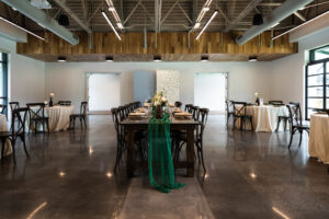 Modern Whimsical Wedding Reception Decor, Long Wooden Feasting Table with Emerald Green Cheesecloth Table Runner, Wooden Cross Back Chairs | Unique Tampa Wedding Venue Florida Ave Brewing