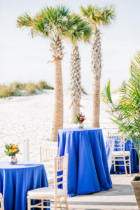 Vibrant Colorful Wedding Ceremony Decor, Blue Table Linens, Small Floral Centerpieces on the Beach, Gold Chiavari Chairs | Tampa Bay Wedding Rentals A Chair Affair | Kate Ryan Event Rentals | Wedding Venue Hilton Clearwater Beach