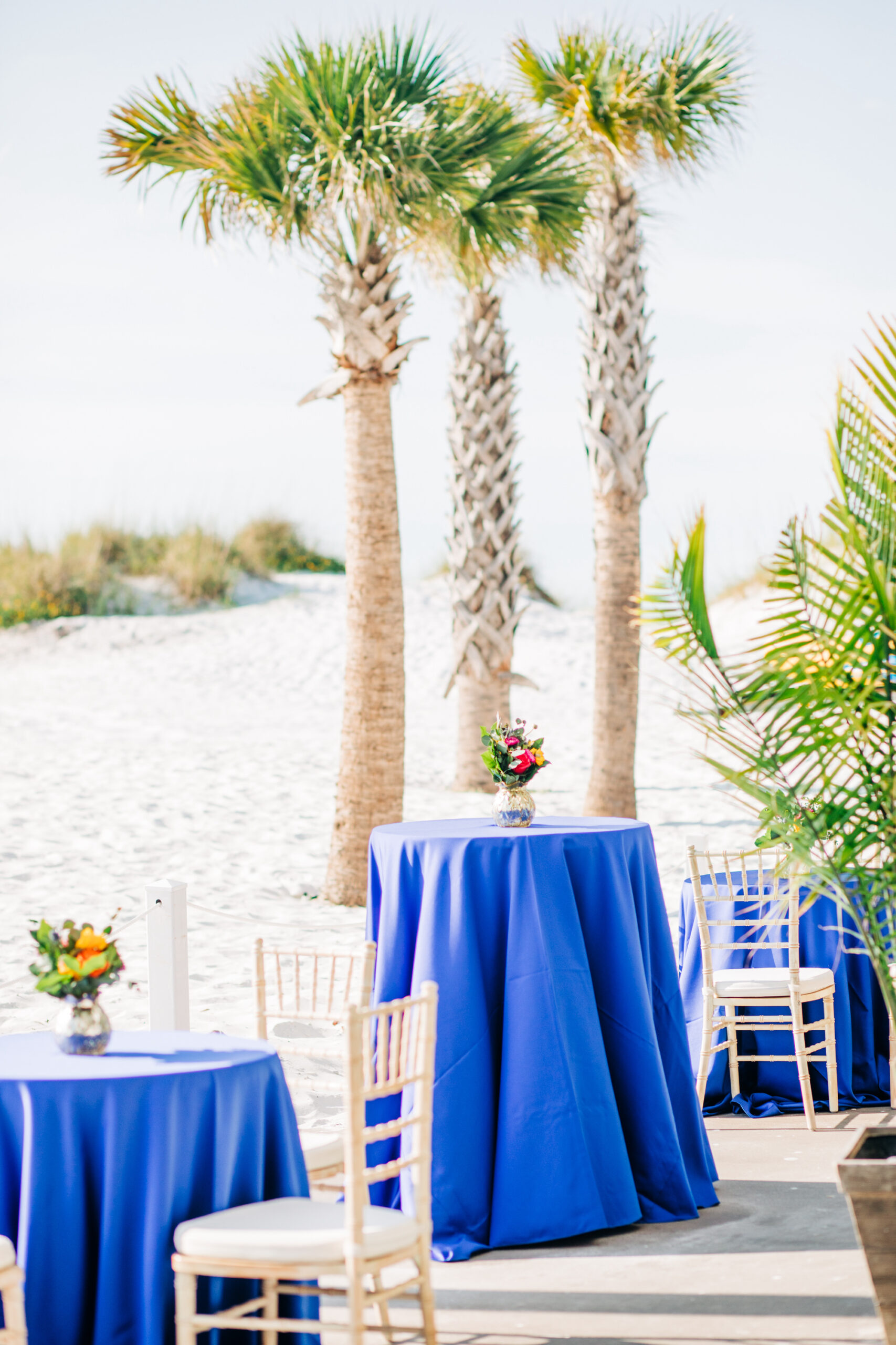 Vibrant Colorful Wedding Ceremony Decor, Blue Table Linens, Small Floral Centerpieces on the Beach, Gold Chiavari Chairs | Tampa Bay Wedding Rentals A Chair Affair | Kate Ryan Event Rentals | Wedding Venue Hilton Clearwater Beach