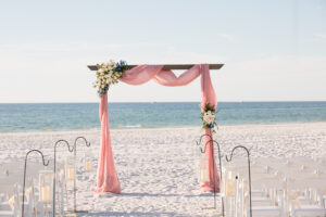 Classic Simple Wedding Beach Ceremony Decor, Hanging Candles on Stakes Lining Aisle, Wooden Arch with Pink Linen and Floral Bouquets | Tampa Bay Wedding Photographer Carrie Wildes Photography | Wedding Planner Breezin' Weddings