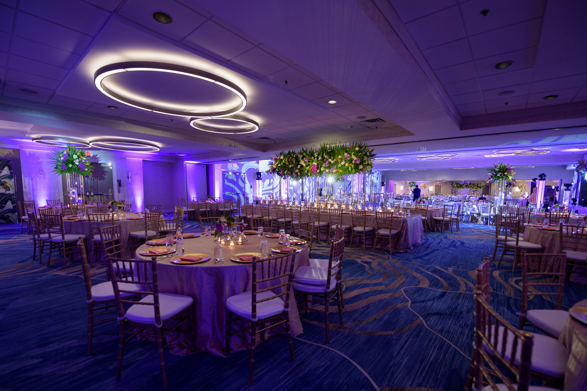 Modern Ballroom Indian Wedding Reception and Tall Centerpieces with Long Feasting Tables and Purple Uplighting | Tampa Bay Venue Hilton Clearwater Beach Resort and Spa | Gabro Event Rentals