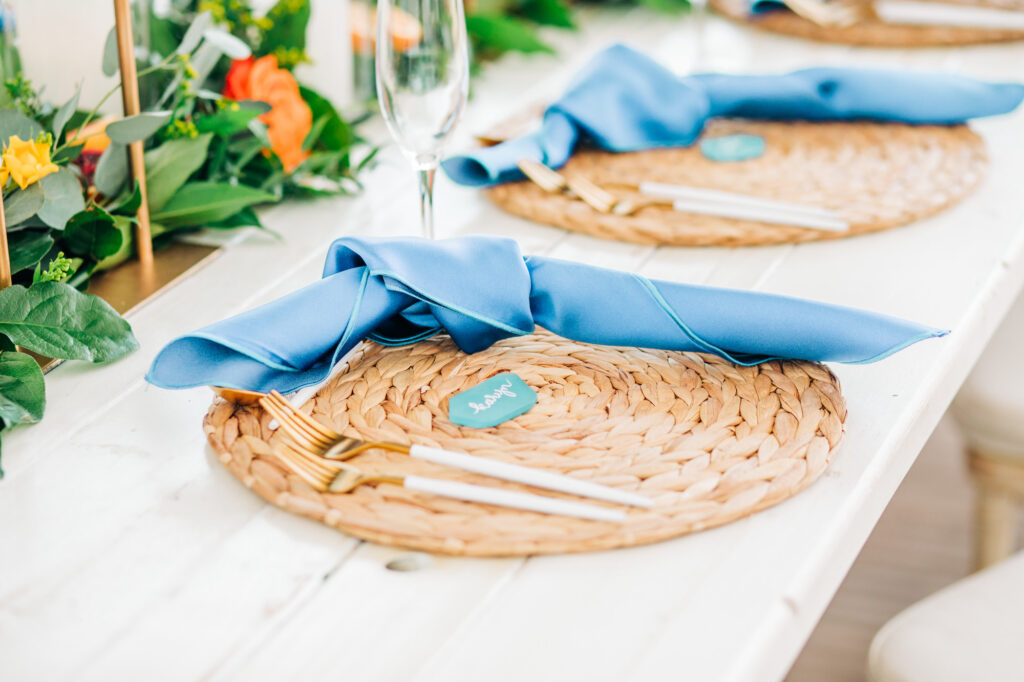 Vibrant Colorful Wedding Reception Decor, Natural Braided Grass Charger Plate, Dusty Blue Linen Napkin, White and Gold Silverware | Tampa Bay Wedding Rentals Kate Ryan Event Rentals