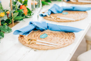 Vibrant Colorful Wedding Reception Decor, Natural Braided Grass Charger Plate, Dusty Blue Linen Napkin, White and Gold Silverware | Tampa Bay Wedding Rentals Kate Ryan Event Rentals