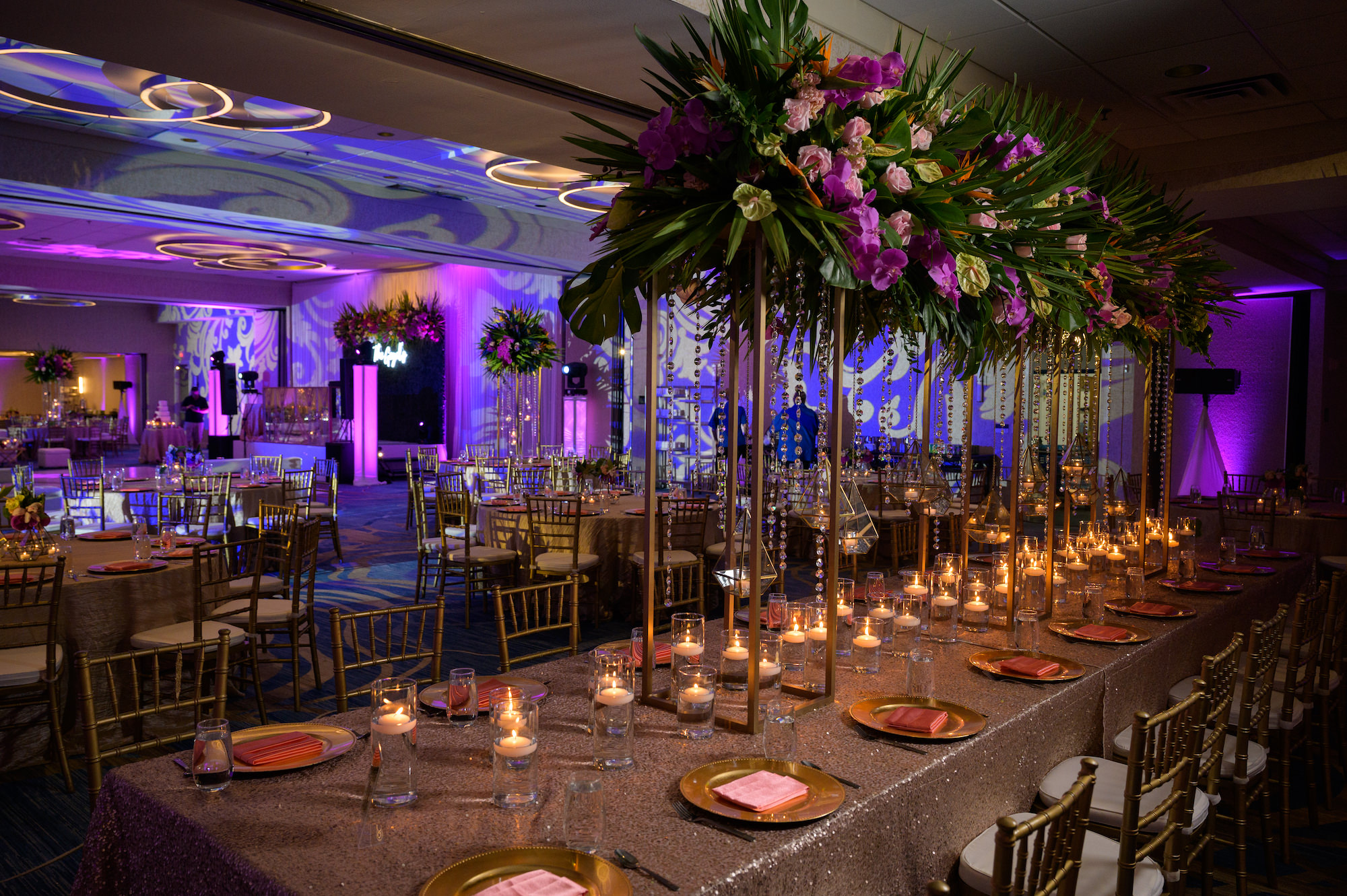 Tropical Wedding Reception and Decor with Tall Floral Centerpieces and Gold Linens Chivari Chairs, Tropical Florals with Fuchsia, Bright Pink, Orange, Purple and Green, Large White Dance floor with Gold Monogram | Tampa Bay Indian Wedding Venue Hilton Clearwater Beach Resort and Spa | Gabro Event Rentals