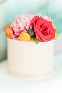Vibrant Colorful Same Sex Wedding Cake with Red, Yellow and Orange Rose and Pink Peony Flower Cake Topper