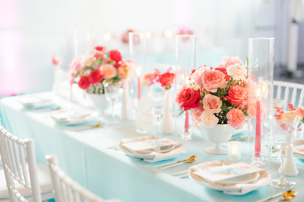 Summer Inspired Wedding Decor, Long Feasting Table with Turquoise Table Linen, White Chiavari Chairs, White and Gold Flatware, Low Pink and Fuchsia Roses Floral Centerpieces, Pink Candlesticks | St. Pete Beach Wedding Rentals Gabro Event Services