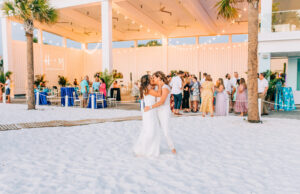 Vibrant Colorful Same Sex Lesbian Wedding Reception, Brides Dancing on White Sand Beach with String Lights | Wedding Venue Hilton Clearwater Beach