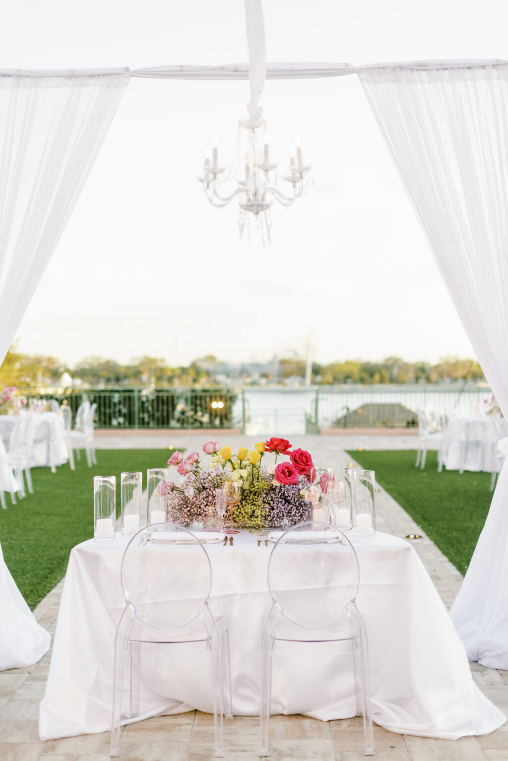 Outdoor Garden Sweetheart Reception Table with Ghost Chairs Chandelier and Romantic Drapery | Tampa Bay Rentals Gabro Event Services | Venue The Vinoy