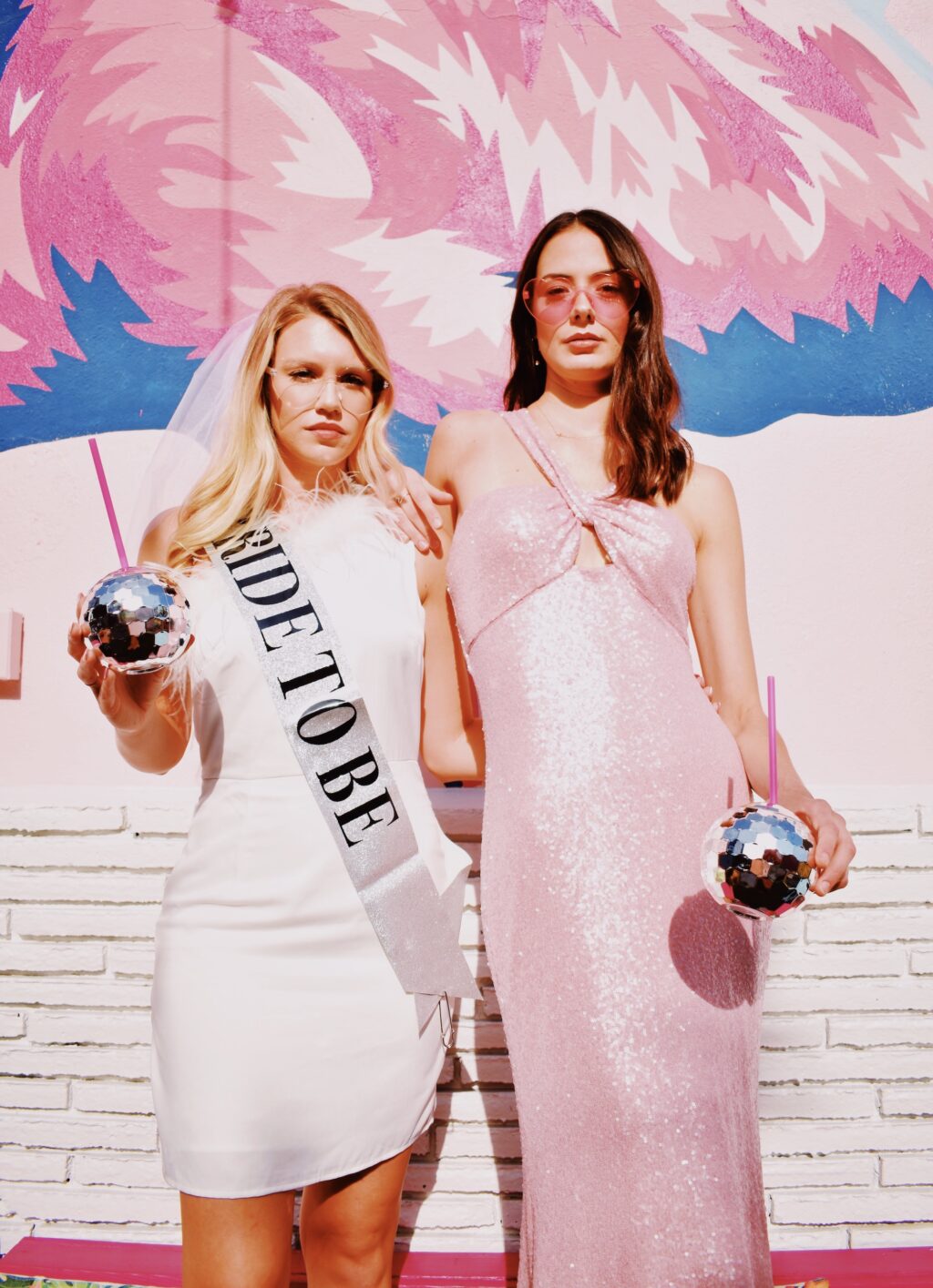Bride with Bride to Be Sash and Bridesmaid in Pink Glitterly Floor Length Dress Holding Disco Cups During Bachelorette Party in Downtown St. Petersburg Florida | Florida Photographer The Gadabouts Captures