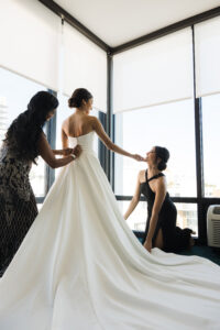 Classic Bride Getting Buttoned Up in Wedding Dress with Mother and Bridesmaid | Tampa Bay Wedding Hair and Makeup Femme Akoi Beauty Studio