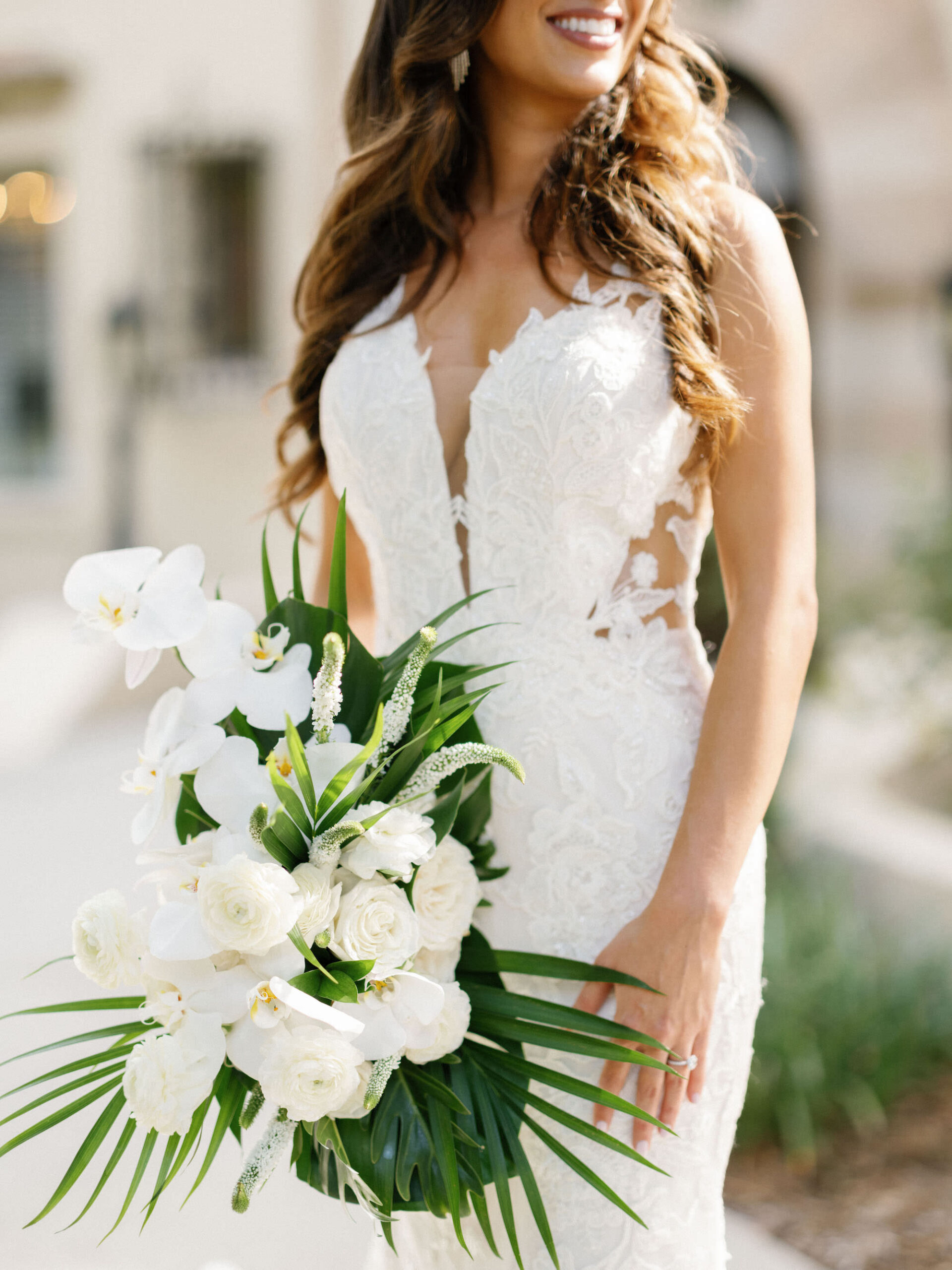 Luxurious Bride Wearing Lace and Illusion Wedding Dress Holding Classic Tropical White Roses and Orchids Flowers with Monstera Leaves and Palm Fronds | Tampa Bay Wedding Florist Botancia International Design Studio