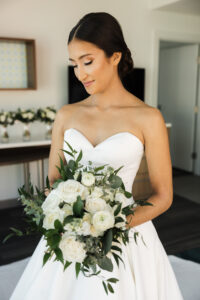Classic Bride with Bun Updo Wearing Strapless Sweetheart Neckline Simple Ballgown Wedding Dress Holding White Roses and Greenery Leaves Floral Bouquet | Tampa Bay Wedding Hair and Makeup Femme Akoi Beauty Studio | Wedding Florist Monarch Events and Design